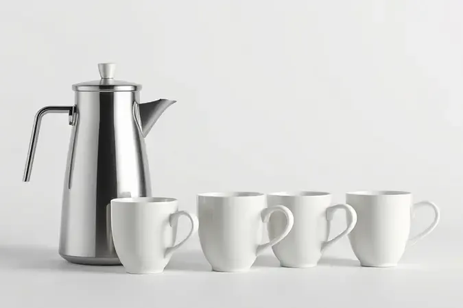 Jarra de inox ao lado de xícaras de café em diferentes tamanhos representando capacidade ideal.
