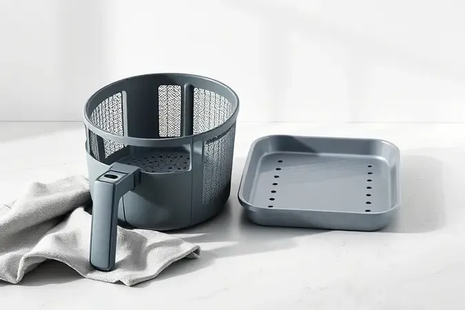 Renderização 3D de cesto de airfryer com superfícies antiaderentes e fácil limpeza em bancada clara.
